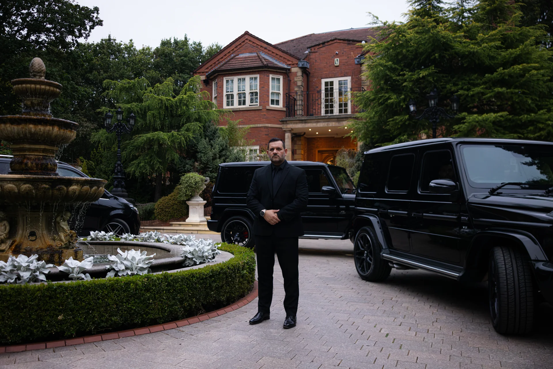 Spartan security professional beside executive vehicles outside a private residence