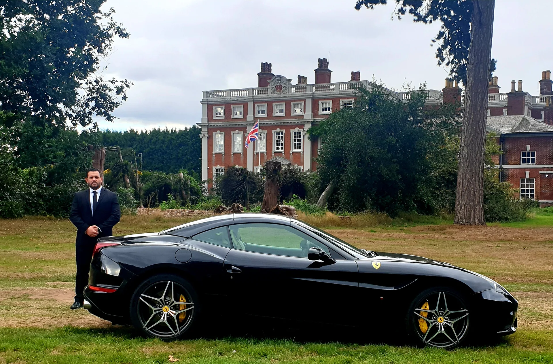Security professional beside an executive car at a country estate